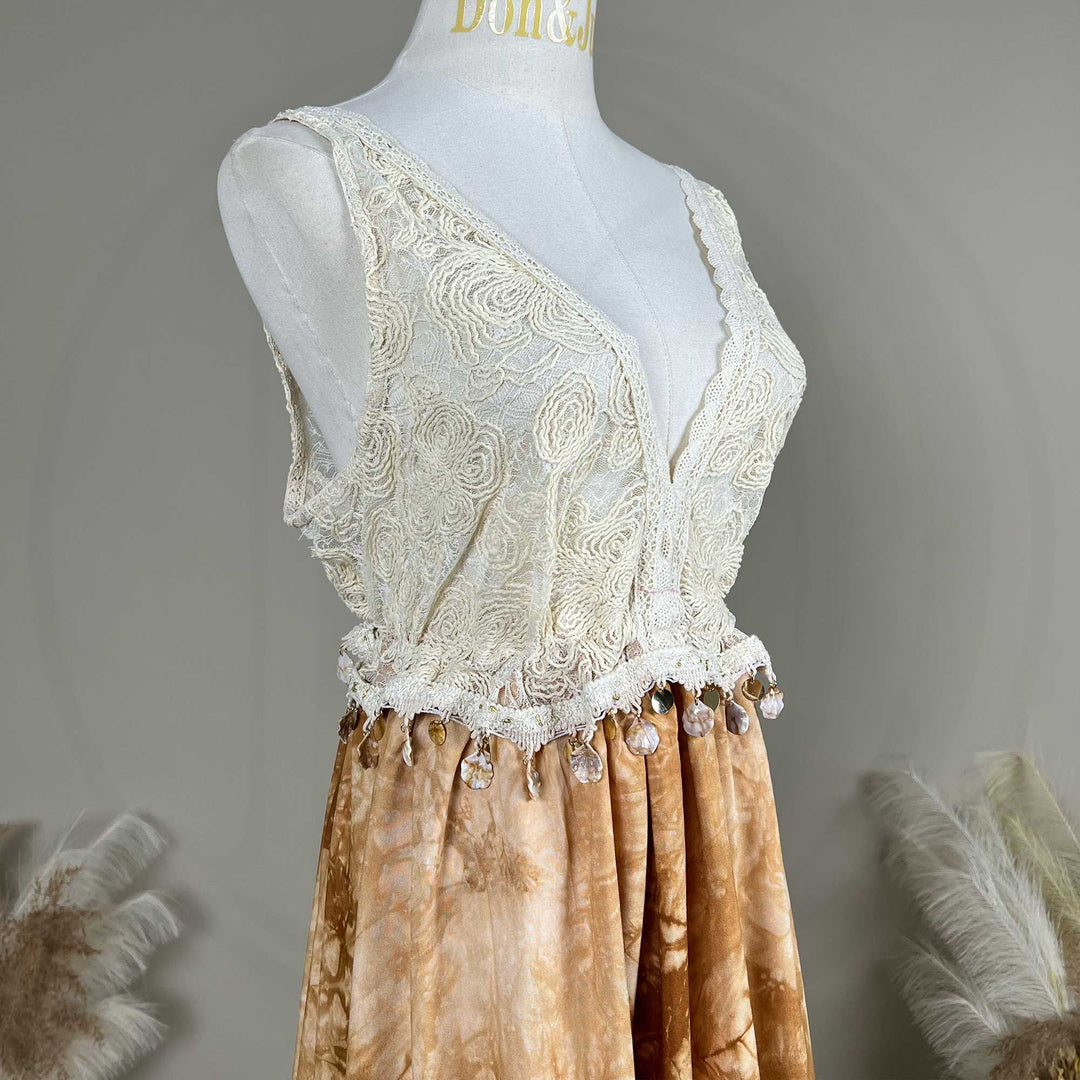 A close up of an Aura white crochet deep-V top with a tie-dye skirt .