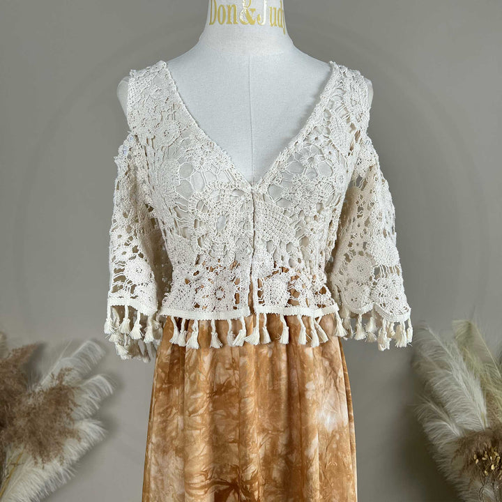 A close up of an Aura white crochet top with a tie-dye skirt.