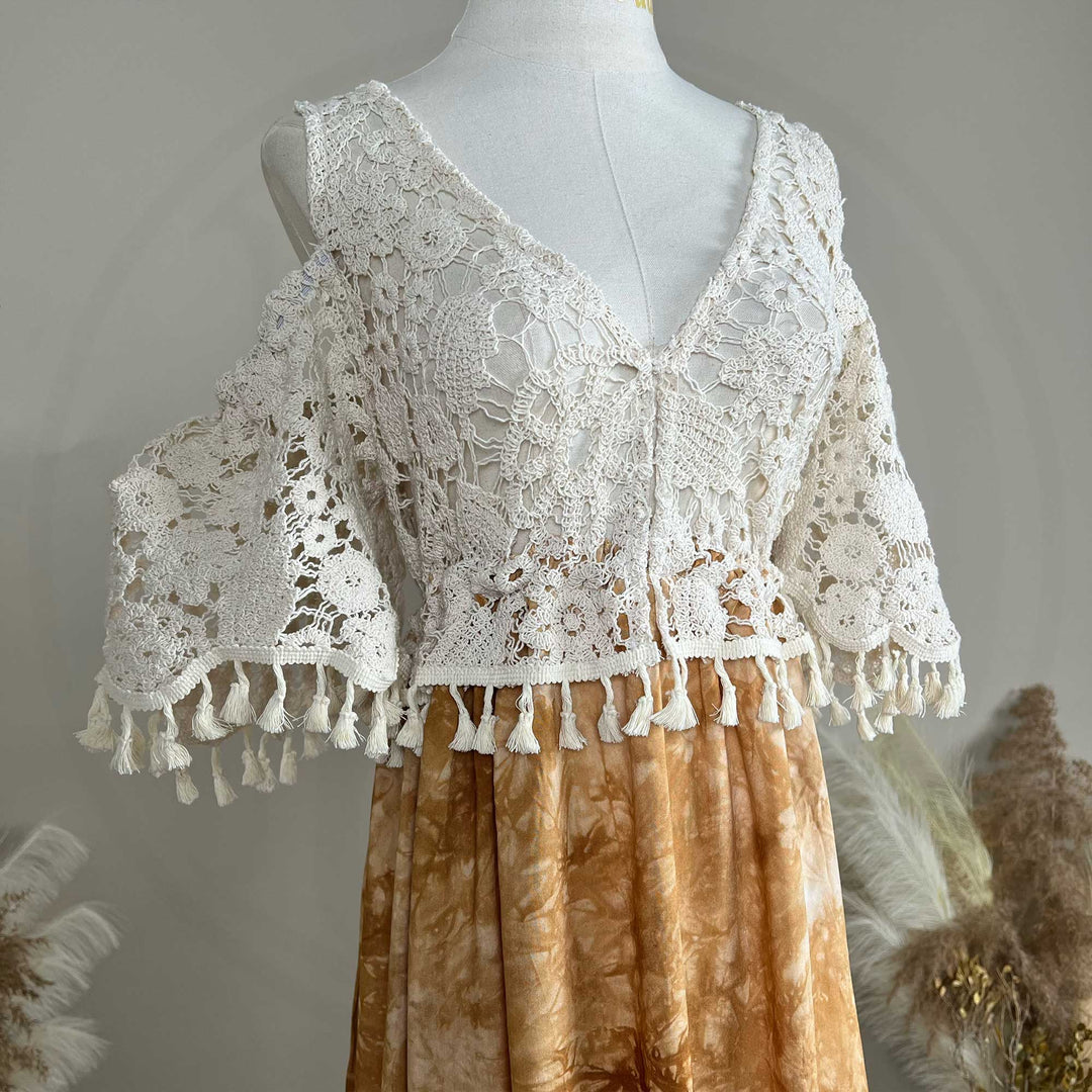 A close up of an Aura white crochet top with a tie-dye skirt.