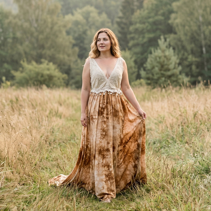 A woman stands in a grassy field wearing an Aura tie-dye gown with a white crochet top.