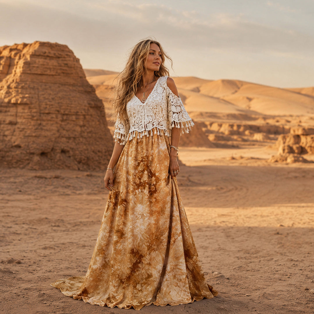 A woman stands in a desert wearing aan Aura tie-dye gown with a crochet top.