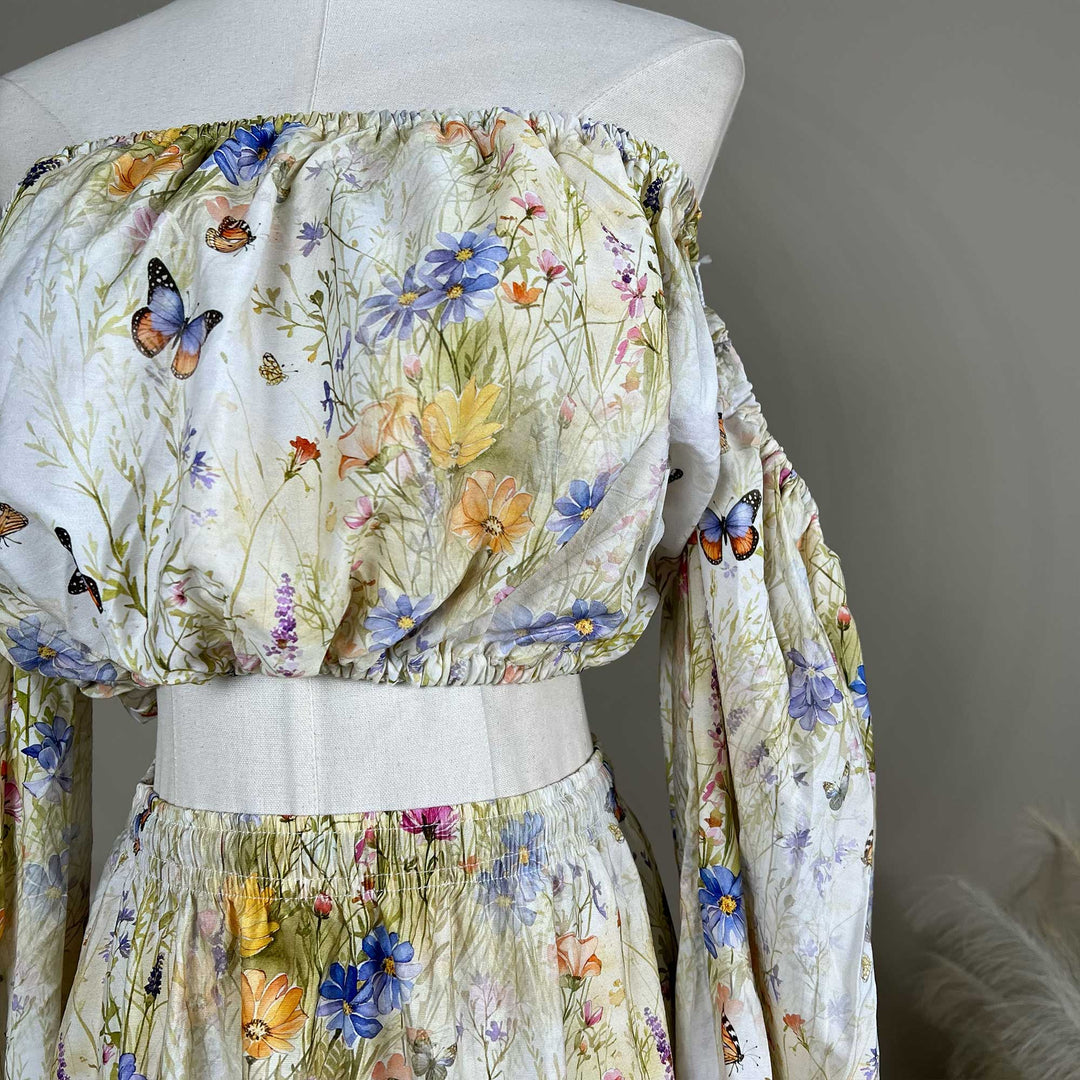 Close up of an Aurelia floral and butterfly print off-shoulder two-piece is displayed on a mannequin.