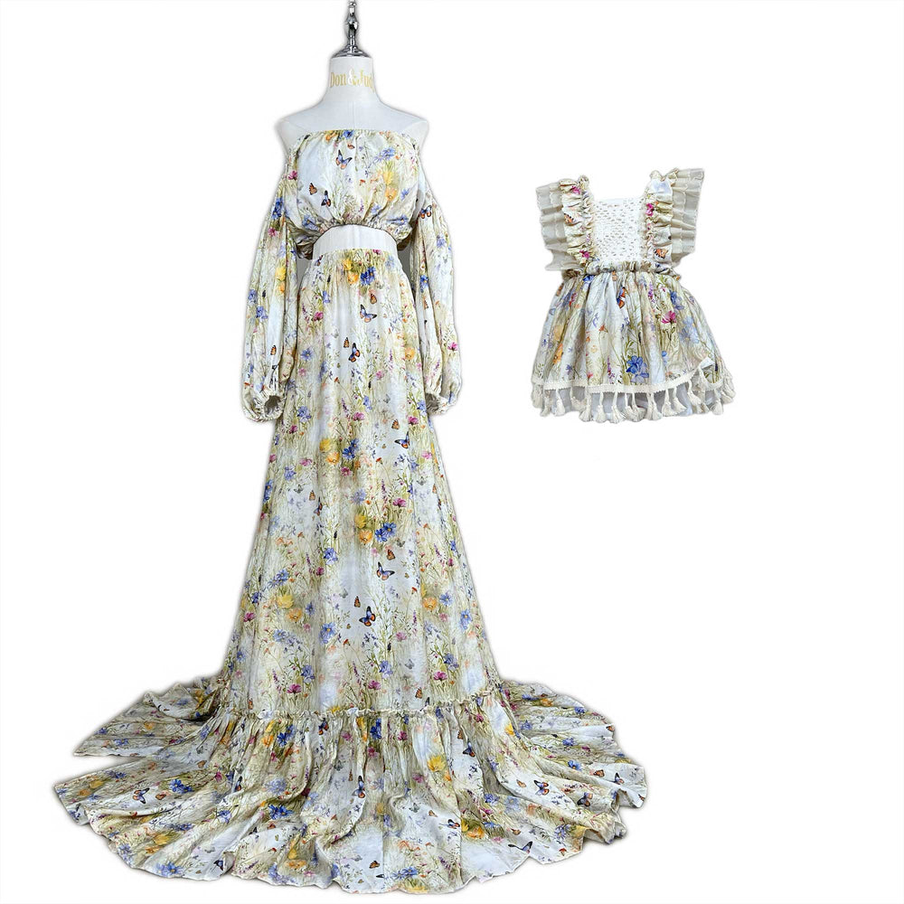 An Aurelia floral and butterfly print off-shoulder gown and matching children's wear are displayed on mannequins.