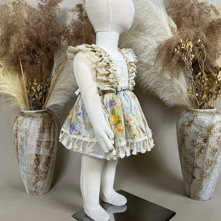 A side view of an Aurelia floral tassel dress hangs on a mannequin