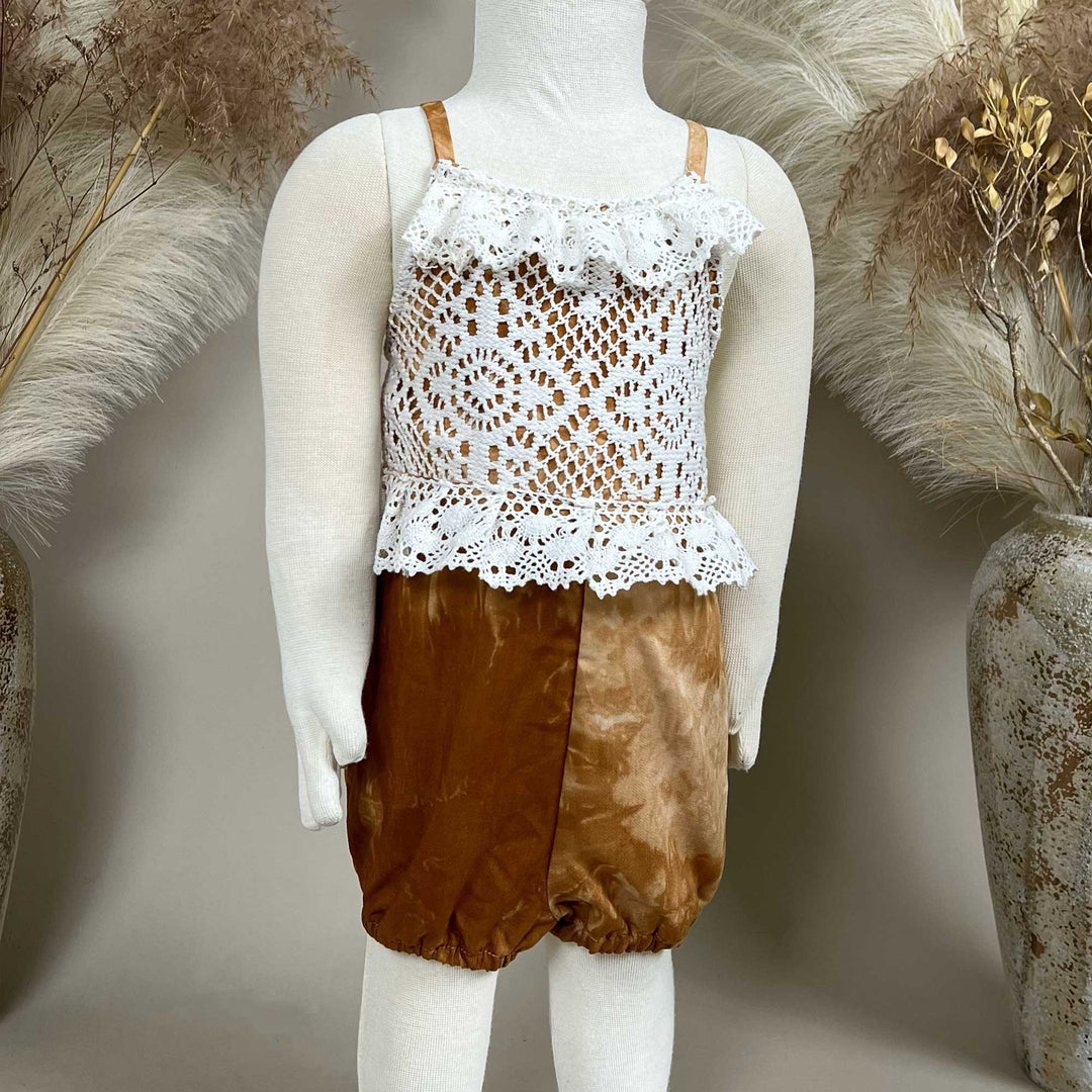 A mannequin displays a Brizo coffee tie-dye romper with a white lace top.
