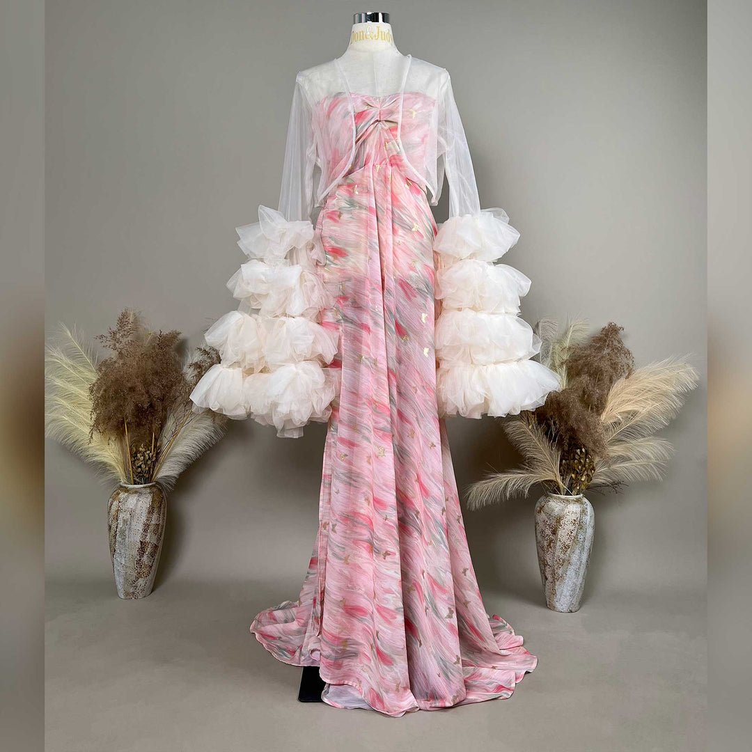 A mannequin displays a Eileithyia pink printed strapless gown with sheer white long sleeves and tiered cuffs; the dress features a train.