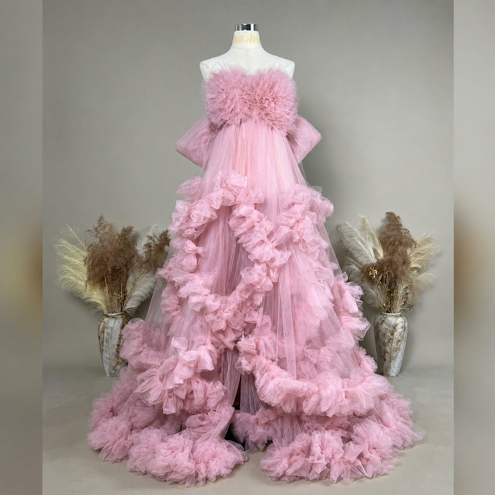 A mannequin displays a Electra pink strapless ruffled tulle gown; the dress features multi-layered ruffles and a train.