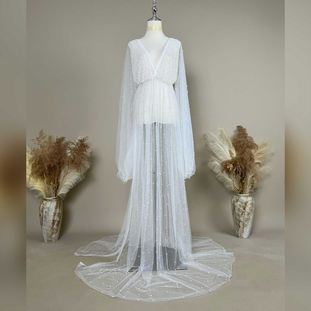 A mannequin displays a Eos ivory deep-V beaded bodysuit with a sheer skirt; the dress features lantern sleeves and pearl embellishments.