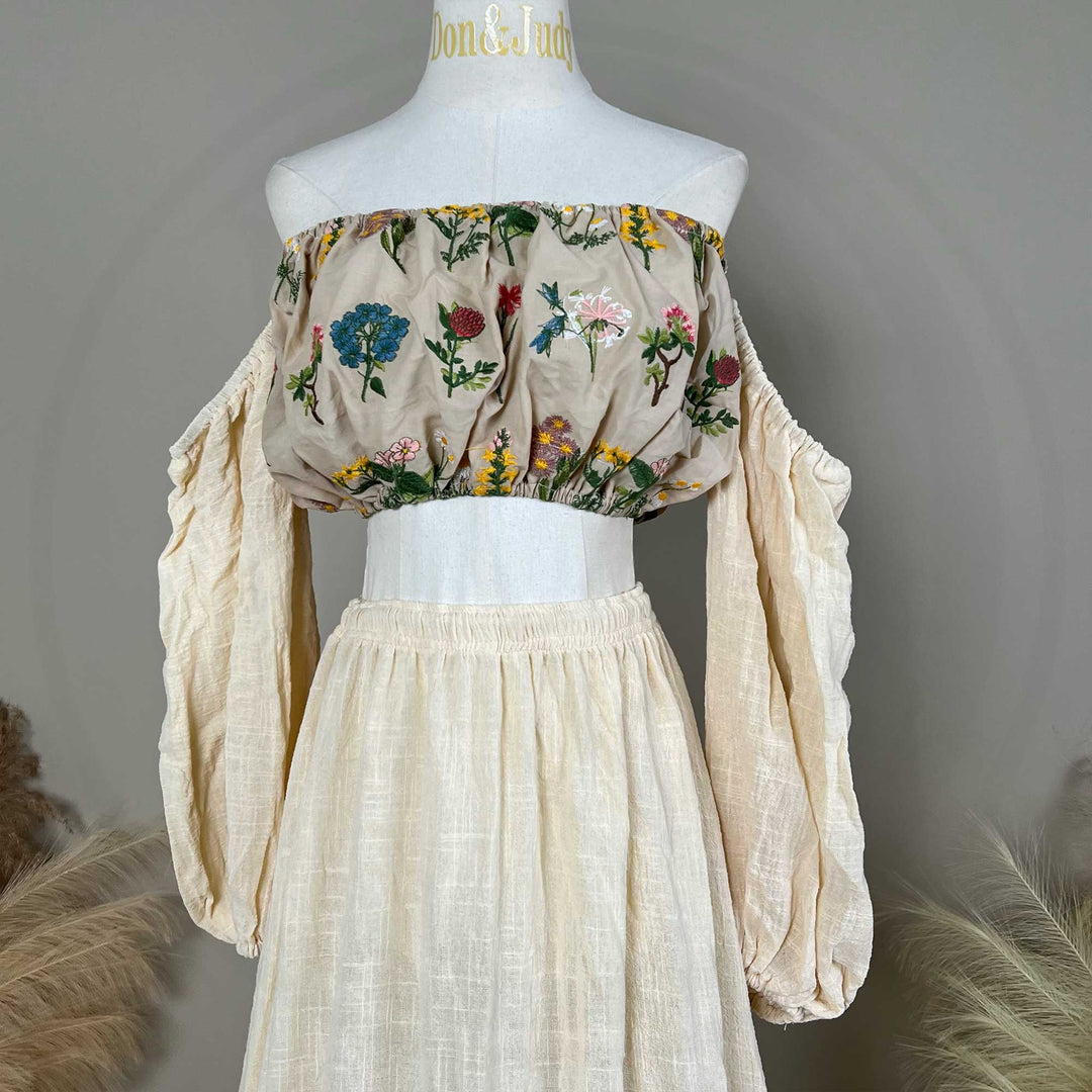 A mannequin displays a Freda beige floral embroidery off-shoulder 2 pieces set.