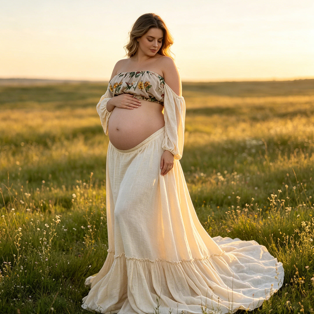 A pregnant woman stands in a grassy field wearing a Freda beige boho embroidery floral two-piece set gown, holding her belly.