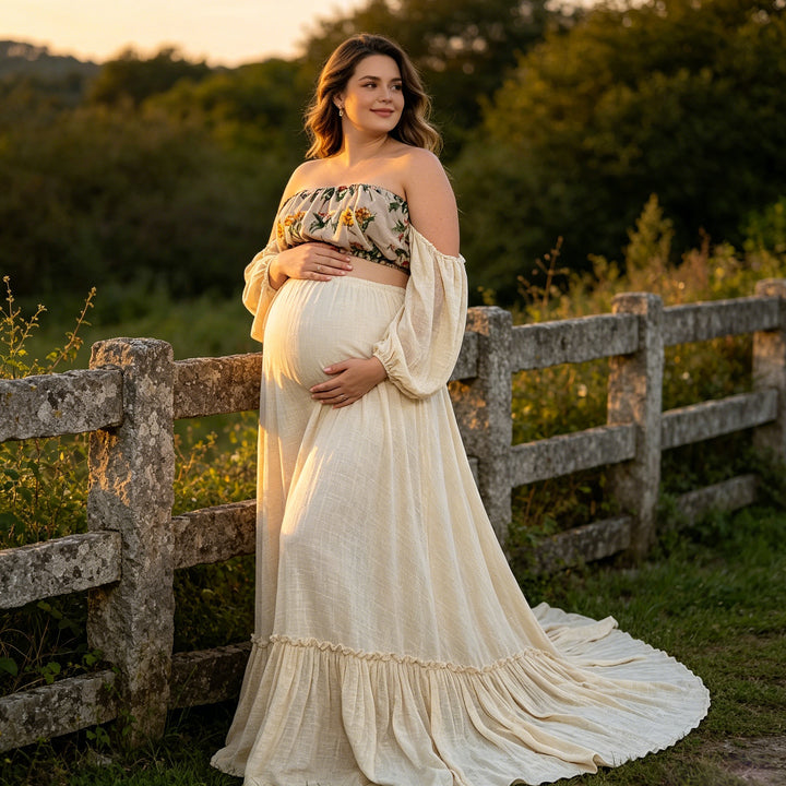 A pregnant woman in a Freda beige floral off-shoulder top and skirt stands by a wooden fence, holding her belly.