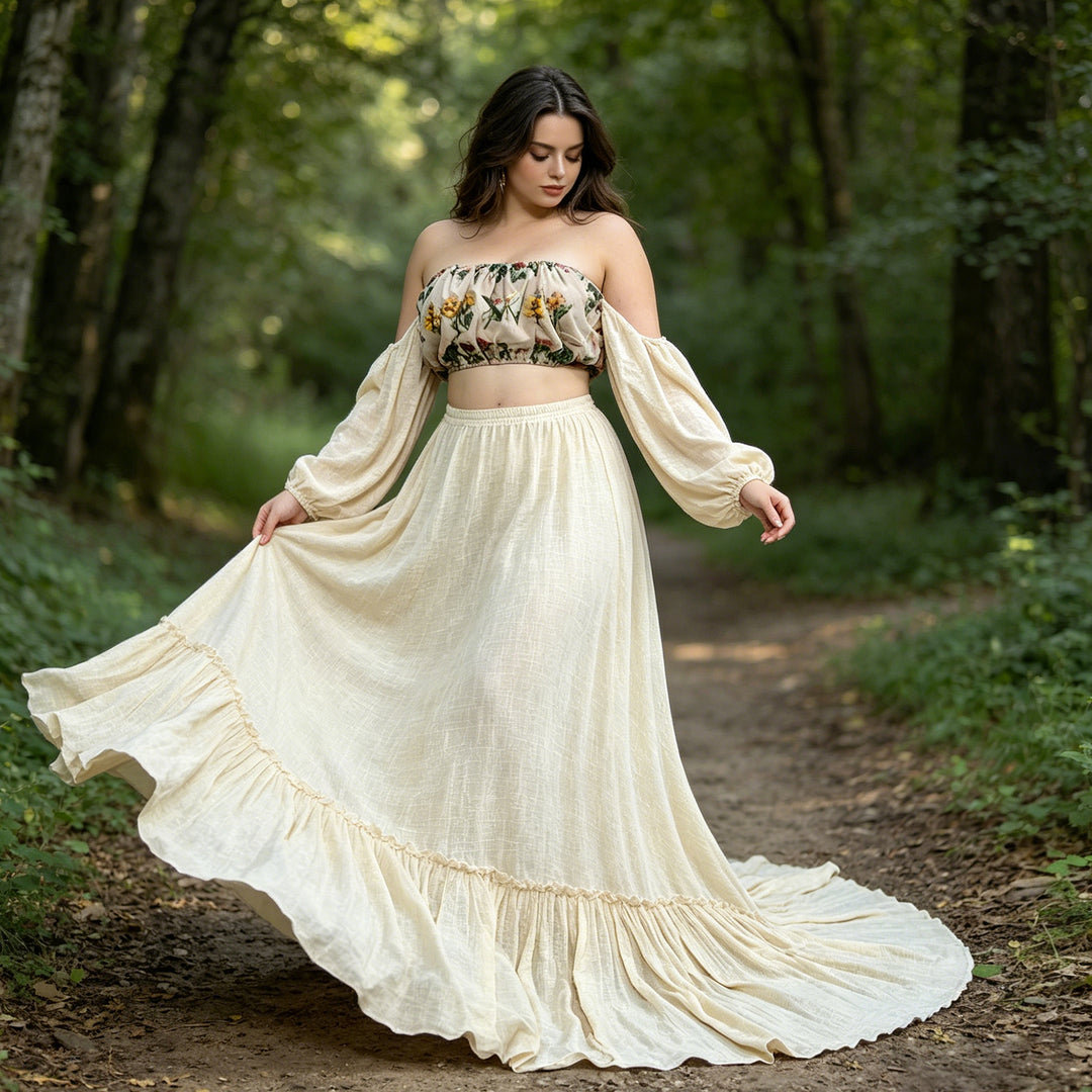 A woman in a Freda floral top and long skirt lifts her skirt while standing on a forest path.she looks down at the ground.