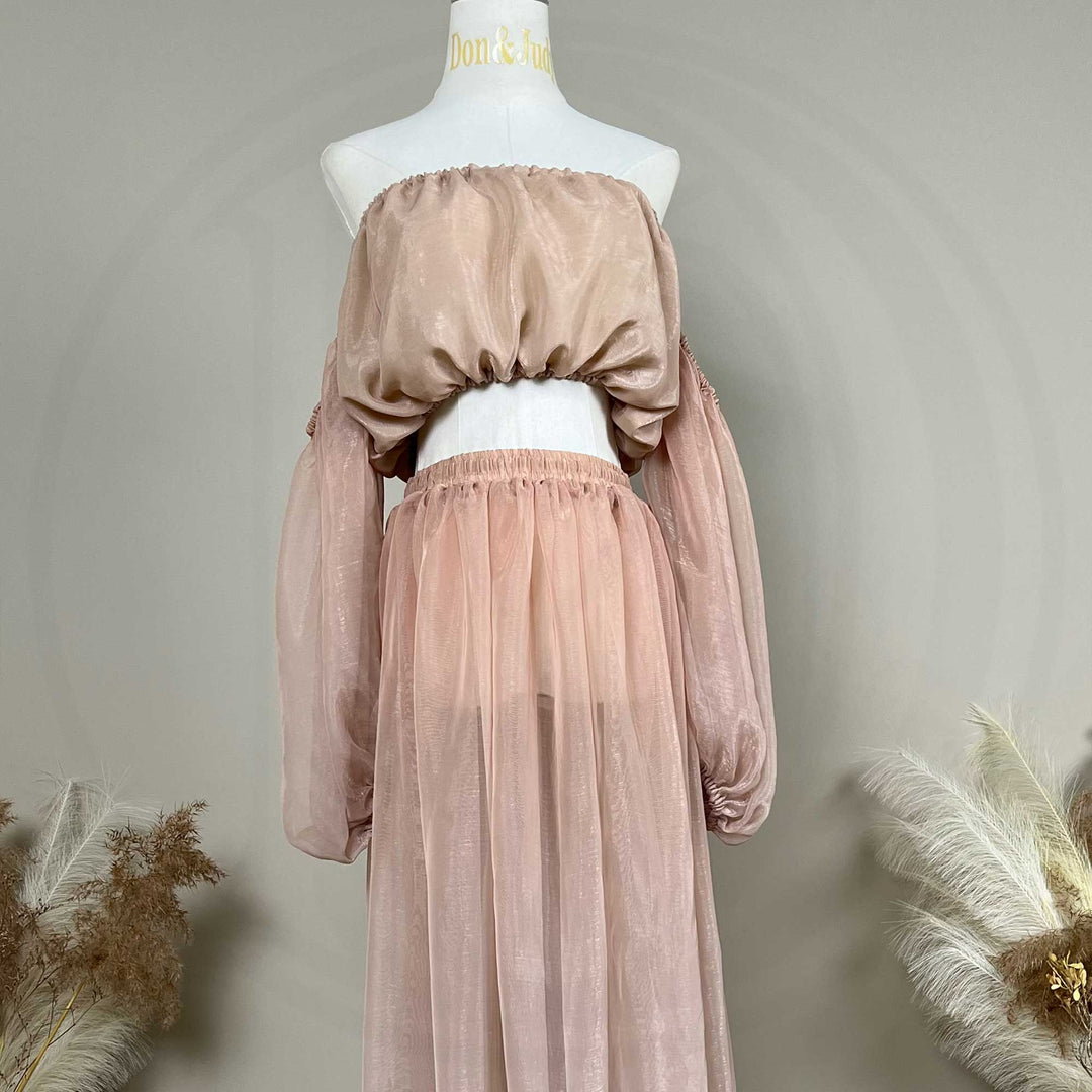 A mannequin displays a Hecate two-piece maternity set featuring an off-shoulder top and floor-length tulle skirt; the top has lantern sleeves.