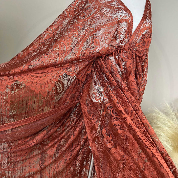 A mannequin displays a close-up of a  Hemera terracotta lace cape featuring floral openwork texture and a deep V-neck; the fabric is semi-transparent mesh.