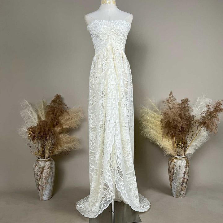 A mannequin displays a Hippolyta beige strapless lace gown with a ruched bodice and train; the dress features an openwork pattern.