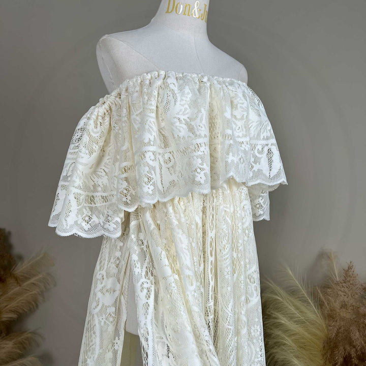 A mannequin displays a side view of a Kymopoleia beige off-shoulder lace gown with ruffled sleeves and a train