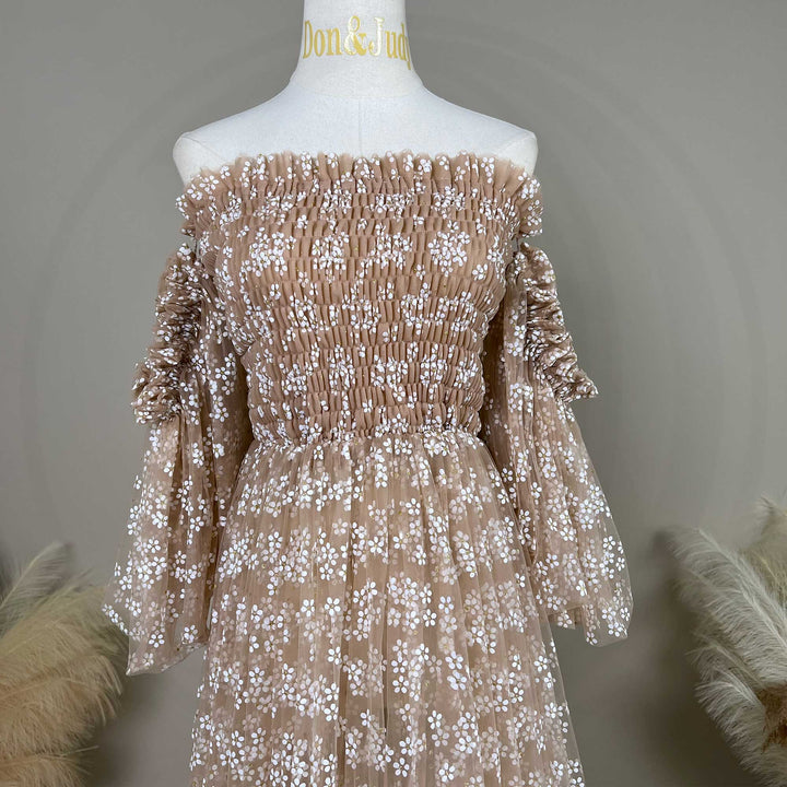 A Lysianassa khaiki tulle dress with floral embroidery is displayed on a white mannequin torso. The dress features an off-the-shoulder neckline with shirred bodice detailing, long sleeves with gathered cuffs.
