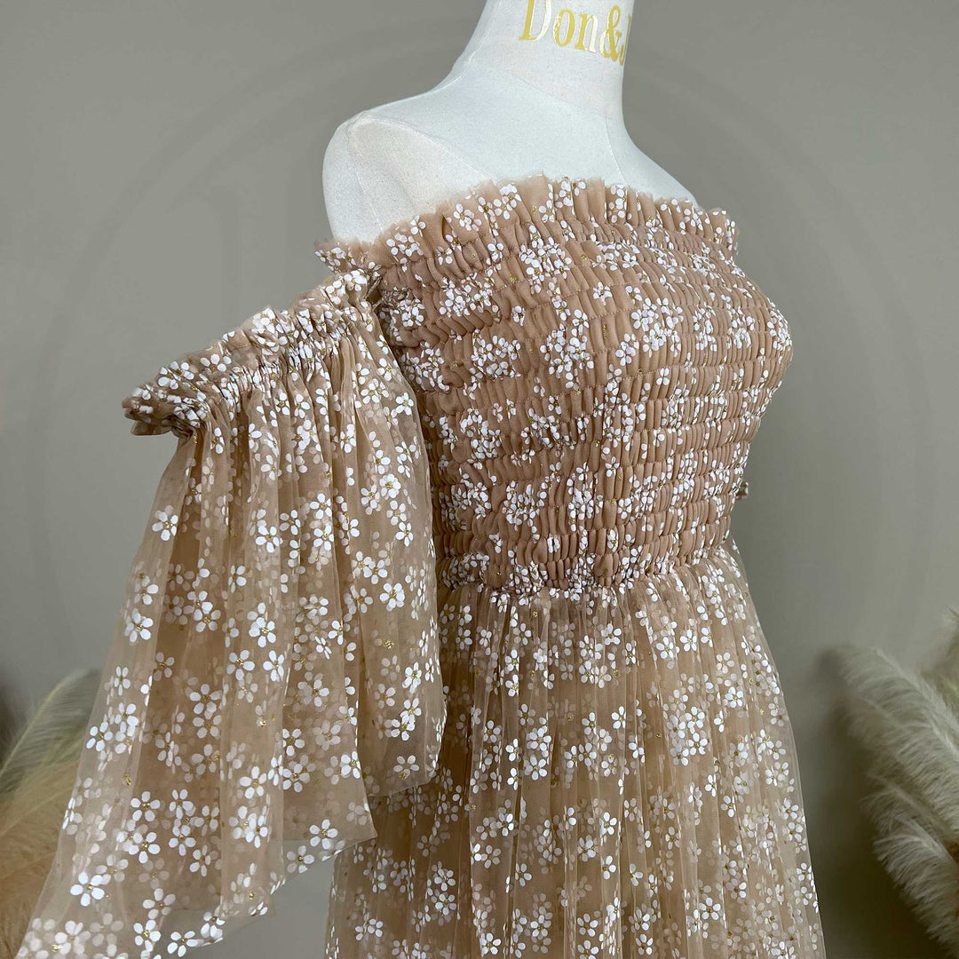 A Lysianassa khaiki tulle dress with white floral embroidery and accents is displayed on a white mannequin torso. The dress features a shirred off the shoulder bodice, puffy sleeves details.