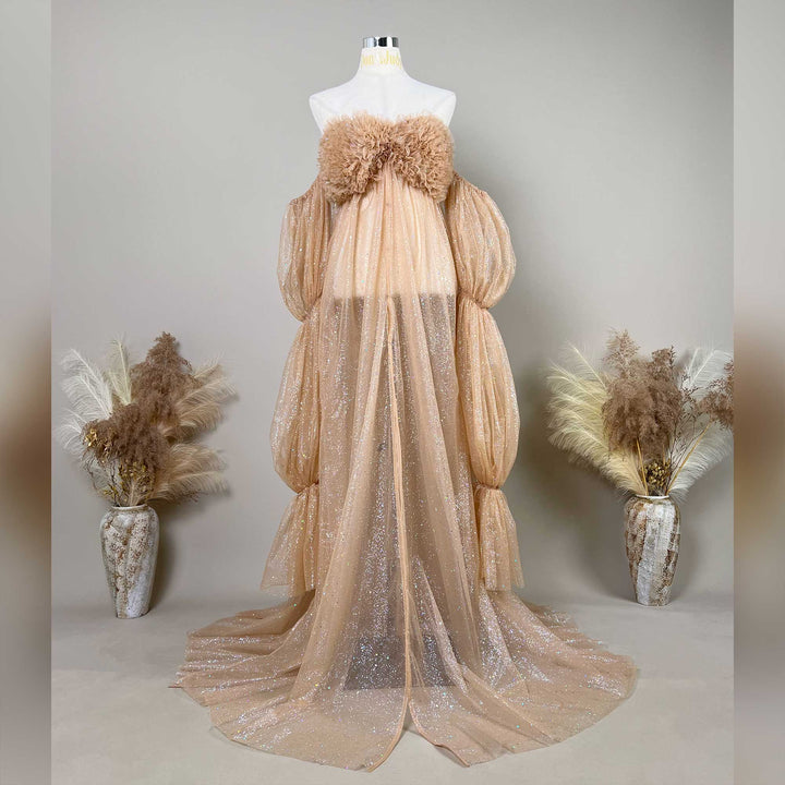 A mannequin displays a Nyx khaki sequined off-shoulder gown with feather chest decor and segmented puff sleeves.