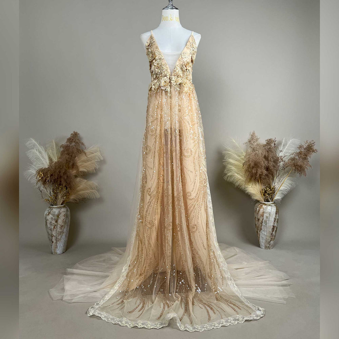 A mannequin displays a Pandia gold spaghetti strap gown with a deep V-neck, 3D floral decorations, and a train skirt.