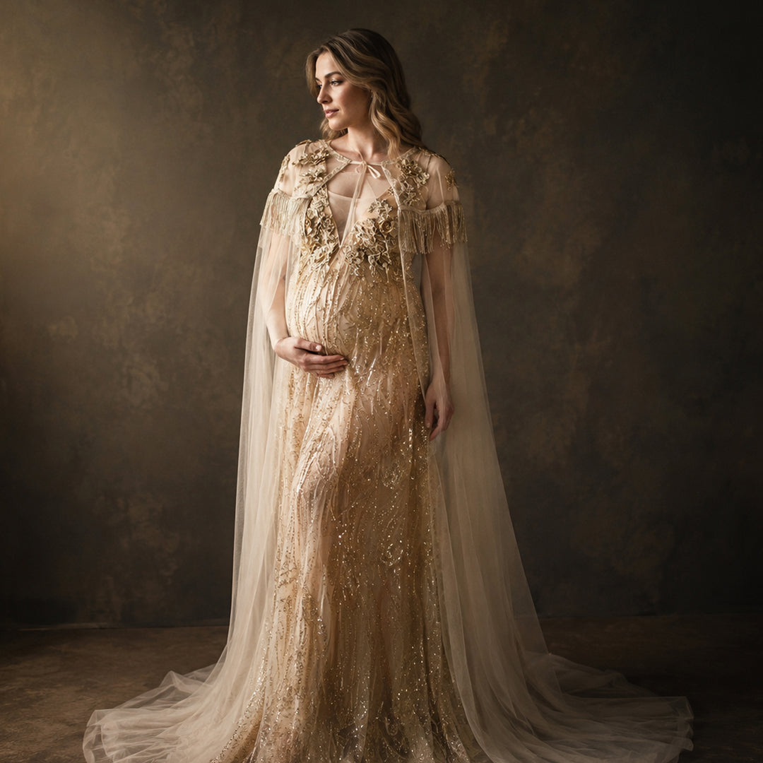 A pregnant model displays a Pandia gold sequined gown with a tulle cape, featuring 3D floral decorations and a train skirt.